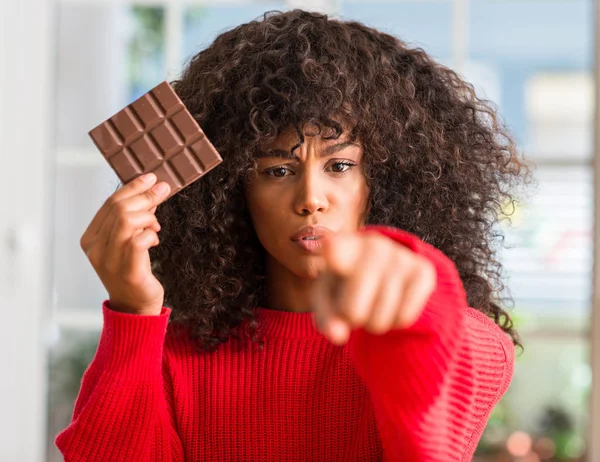 Mujer Afroamericana Comiendo Barra Chocolate Casa Señalando Con Dedo Cámara —  Fotos de Stock