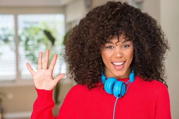 African american woman wearing headphones showing and pointing up with fingers number five while smiling confident and happy.