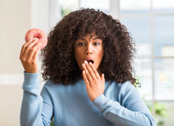 Mujer Afroamericana Sosteniendo Rosquilla Casa Boca Cubierta Con Mano Conmocionada — Foto de Stock