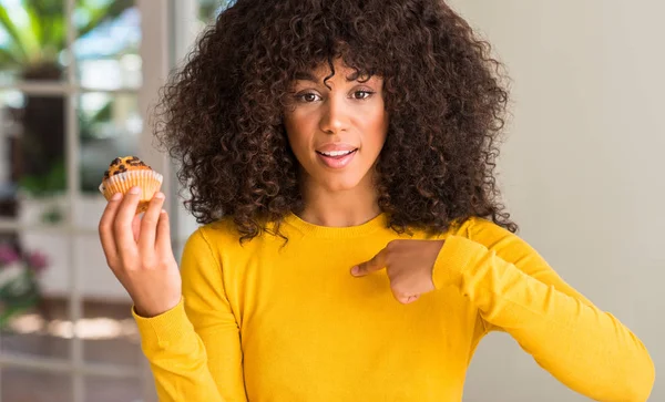Mujer Afroamericana Sosteniendo Magdalena Chocolate Con Cara Sorpresa Señalando Dedo — Foto de Stock