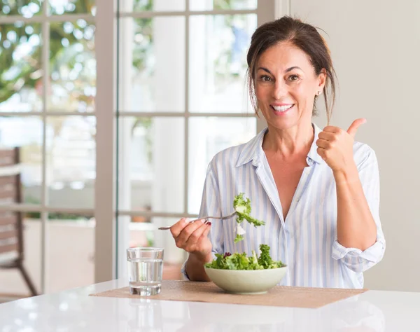 Mulher Meia Idade Comendo Salada Fresca Uma Tigela Casa Apontando — Fotografia de Stock