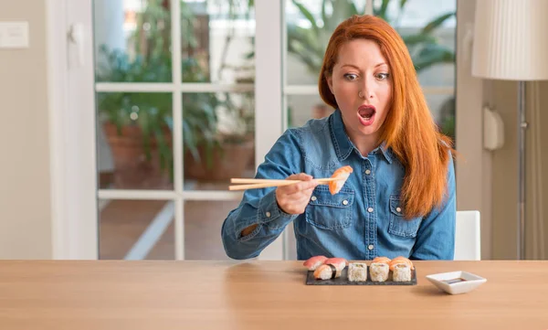 Redhead Woman Eating Sushi Using Chopsticks Scared Shock Surprise Face — Stock Photo, Image