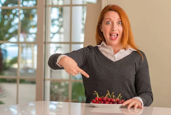 Mulher Ruiva Comendo Cerejas Casa Muito Feliz Apontando Com Mão — Fotografia de Stock