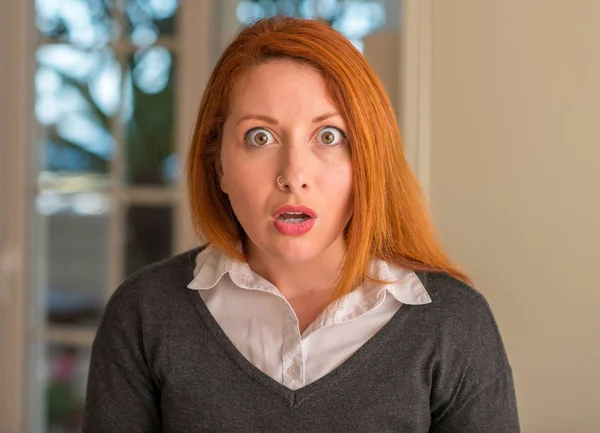 赤毛の女性自宅驚き顔でショックで怖い怖いと恐怖の表情で興奮 — ストック写真
