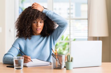 Afrikalı-Amerikalı kadın evde eğitim ile vurguladı bir bilgisayar dizüstü kullanarak kafasına, utanç ile şok el ve yüz, öfkeli ve sinirli sürpriz. Korku ve hata için üzgün.