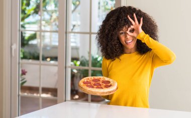 Afrikalı-Amerikalı kadın mutlu yüz el parmaklarının arasından seyir göz üzerinde ok işaretiyle yapıyor gülümseyen lezzetli biberli pizza evde yemek hazır