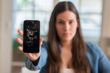 Kendinden emin bir ifade ile kırık smartphone ciddi düşünme acımak yüz tutan esmer genç kadın