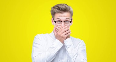 Genç yakışıklı sarışın adam ağız hata için elleriyle kapsayan şok. Gizli kavramı.