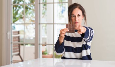 Orta yaşlı kadın kamera ve size parmak ile işaret bar çikolata yeme, el işareti, pozitif ve kendinden emin bir jest ön