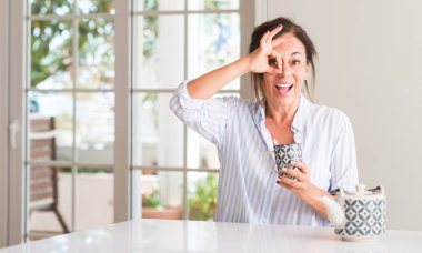 Orta yaşlı kadın ile mutlu yüz el parmaklarının arasından seyir göz üzerinde ok işaretiyle yapıyor gülümseyen bir fincan çay ya da kahve içme