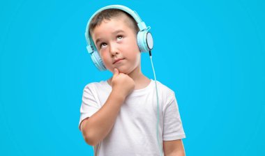 Koyu saçlı küçük çocuk müzik dinleme kulaklık ciddi bir yüz düşünce hakkında soru, çok karışık bir fikir ile