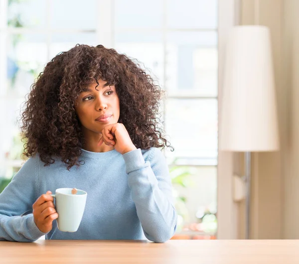 Bir fincan kahve hakkında soru, çok düşünme ev ciddi yüzüne tutan Afrikalı-Amerikalı kadın fikir karışık