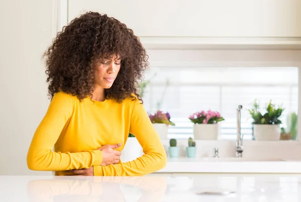 非洲裔美国妇女穿着黄色毛衣在厨房与手在胃因为恶心 痛苦的疾病感到不适 疼痛概念 — 图库照片