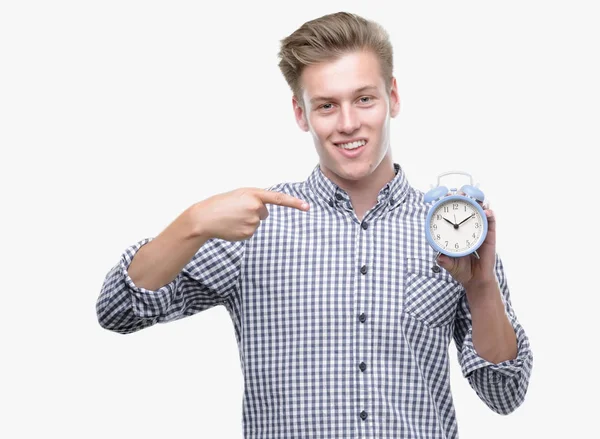 Young Handsome Blond Man Holding Alarm Clock Very Happy Pointing — Stock Photo, Image
