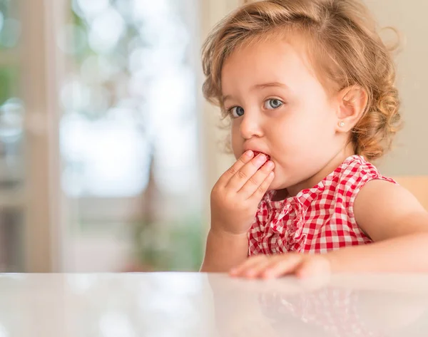 家でイチゴを食べる青い目の美しい金髪の子 — ストック写真