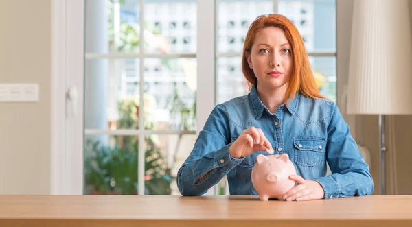 Rödhårig Kvinna Sparar Pengar Spargrisen Hemma Med Självsäker Uttryck Smarta — Stockfoto