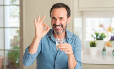 Orta yaş erkek parmak, mükemmel sembolü ile ok işareti yapıyor su içme