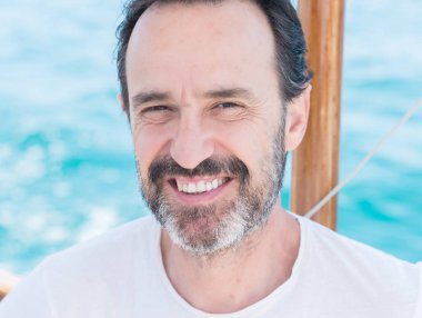 Yelkenli üzerinde seyahat ve mutlu ve kendinden emin gülümseyen kıdemli yakışıklı