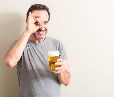 Senior man drinking beer with happy face smiling doing ok sign with hand on eye looking through fingers clipart