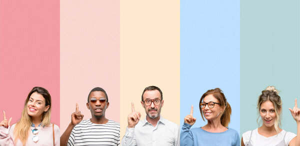 Смешанная группа людей, женщин и мужчин счастливы и удивлены приветствуя, выражая вау жест указывая вверх
