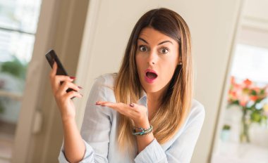 Smartphone işaret, el ile evde tutan genç kadın