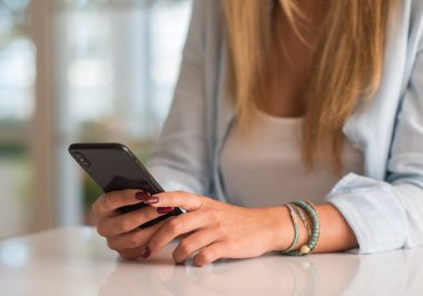 Evde akıllı telefon kullanan bir kadın.