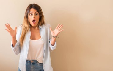 Sürpriz yüz evde duvara yaslanmış bir gömlek giymiş genç güzel kadın.