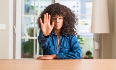 Afrikalı-Amerikalı kadın evde açık eliyle dur işareti ile ciddi ve kendine güvenen ifade, savunma hareketi yapıyor