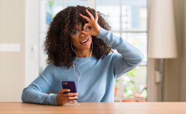 Mutlu yüz el parmaklarının arasından seyir göz üzerinde ok işaretiyle yapıyor gülümseyen ile Smartphone kullanarak güzel bir Afrikalı-Amerikalı kadın