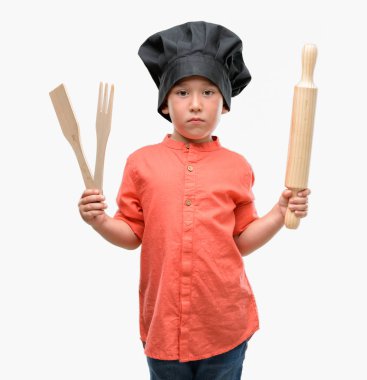 Koyu saçlı küçük çocuk şef üniforması acımak yüz ciddi düşünüyorum üstünde kendine güvenen bir ifade ile