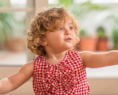 Güzel sarışın çocuk gülümseyen ve yan evde bitki komutunuz ile seyir.