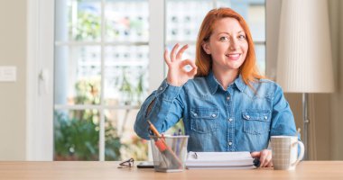 Kızıl saçlı kadın parmakları, mükemmel sembolü olan ok işareti yapıyor evde eğitim