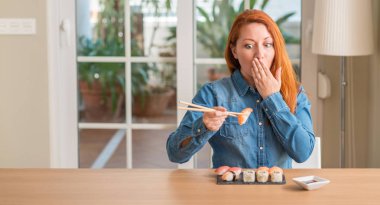 Hata, korku, sessizlik içinde gizli kavramı korkmuş ifade için elle utanç ile şok Chopsticks kapak ağzı kullanarak suşi yemek Kızıl saçlı kadın