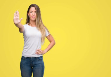 T-shirt ve kot giyen güzel genç kadın dur işareti ile ciddi ve kendine güvenen ifade, savunma hareketi yaparken el açmak