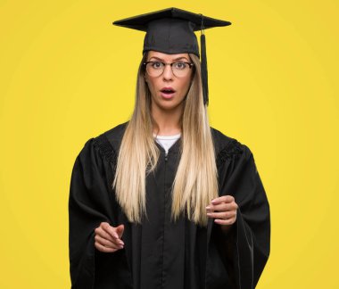 Gözlük ve mezuniyet elbise bir sürpriz yüz, korkuyor ve heyecanlı korku ifadesi ile şok korkmuş giyen güzel genç kadın