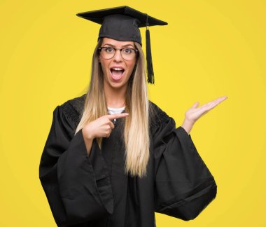 Gözlük ve Mezuniyet cübbesi el ve parmak ile işaret çok mutlu giyen güzel genç kadın