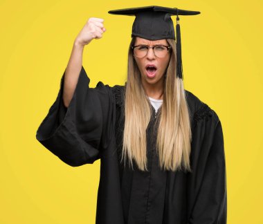 Gözlük ve mezuniyet giyen güzel genç kadın robe rahatsız ve hayal kırıklığına uğramış öfke kavramı ile öfke, çılgın ve yükseltilmiş eliyle diye bağıran bağırarak