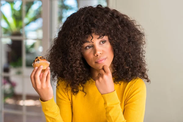 African American Woman Holding Choklad Muffin Allvarligt Ansikte Funderar Frågan — Stockfoto