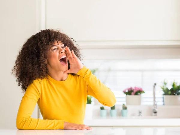 在厨房里穿着黄色毛衣的非洲裔美国妇女大喊着 大声尖叫着 手放在嘴边 沟通理念 — 图库照片