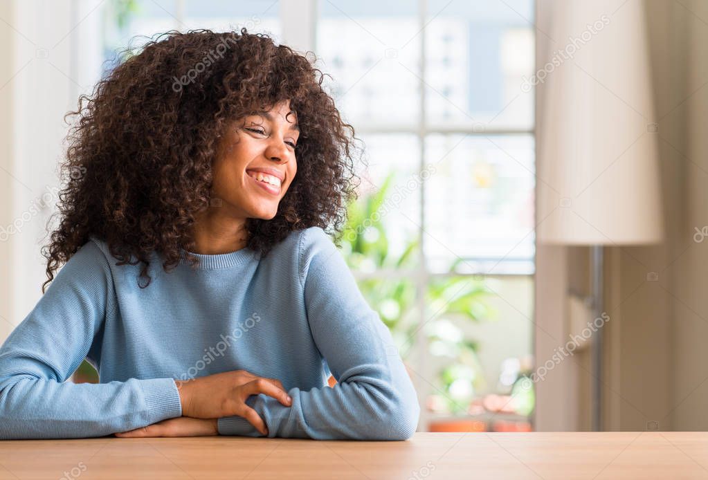 African american woman at home looking away to side with smile on face, natural expression. Laughing confident.