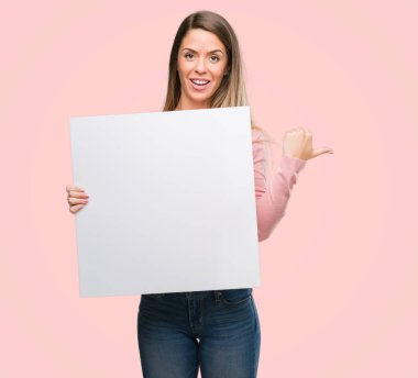 El ve parmak ile yukarı dönük mutlu yüz gülümseyen ile reklam afişi tutan güzel genç kadın