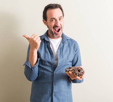 Komuta sizde el ve parmak ile yukarı dönük mutlu yüz gülümseyen ile çikolatalı çörek yeme