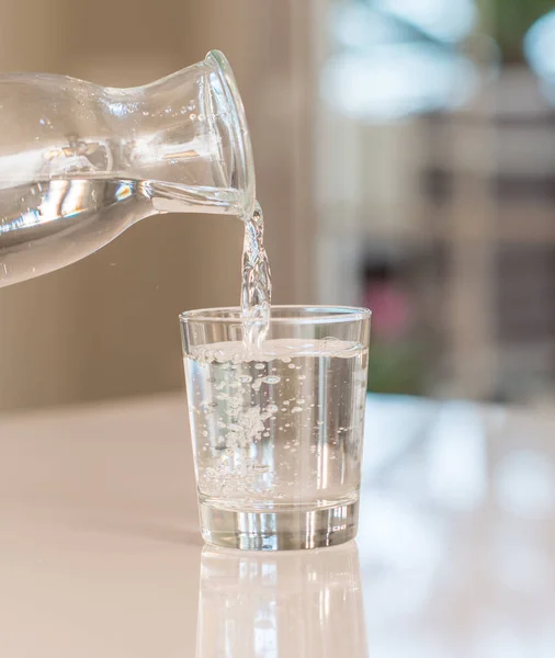 Penutup Botol Menuangkan Air Dalam Gelas Atas Meja Dengan Latar — Stok Foto