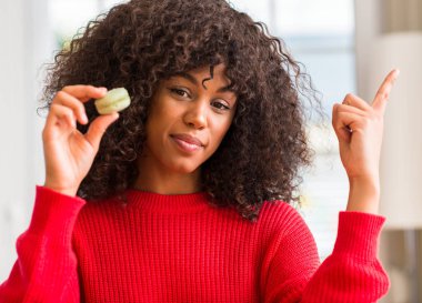 Macaron çok mutlu el ve parmak ile tarafına işaret tutan Afrikalı-Amerikalı kadın