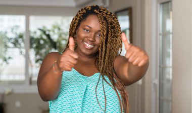 Afrikalı-Amerikalı kadın evde el ile pozitif jest yapıyor onaylama gülümseyen ve başarı için mutlu yaşasın. Kamera, kazanan jest arıyorsunuz.