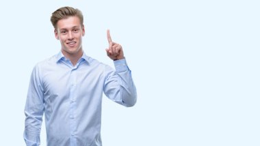 Genç yakışıklı sarışın adam bir fikir ya da soru işaret parmağı ile gülen yüz, sürpriz bir numara