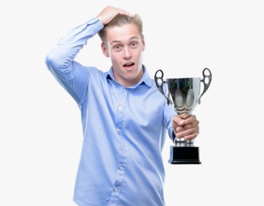 Bir kupa başı üzerinde el ile vurguladı tutan genç yakışıklı sarışın adam şok utanç ve sürpriz suratla, öfkeli ve sinirli. Korku ve hata için üzgün.