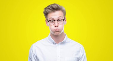 Komik surat ile yanakları şişirme genç yakışıklı sarışın adam. Ağız ile hava, deli ifade şişirilmiş.