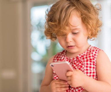 Güzel sarışın çocuk tutarak ve smartphone vasıl ev arıyorum.