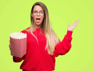 Kocaman bir gülümseme ile çığlık zaferini kutluyor ve ellerini kaldırdı patlamış mısır çok mutlu ve heyecanlı, kazanan ifade yemek güzel genç kadın